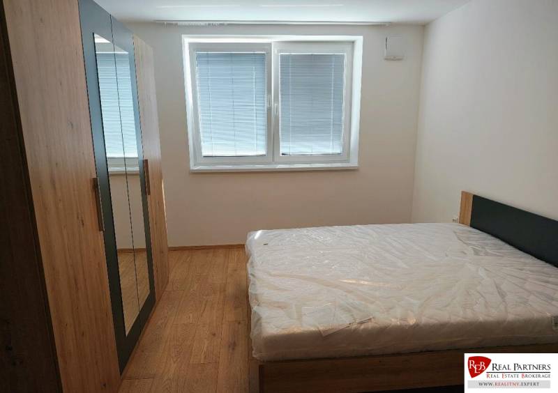 Bedroom in a 3-room apartment with wood-patterned flooring, a bed, and a wardrobe.