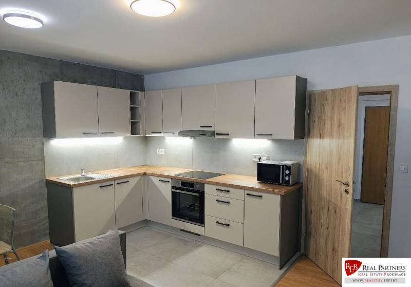 A kitchen in a 3-room apartment with a kitchen unit and a wooden decor floor.
