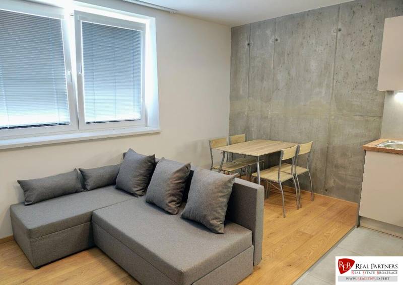 Gray sofa and dining area on a wooden decor floor in a 3-room apartment.