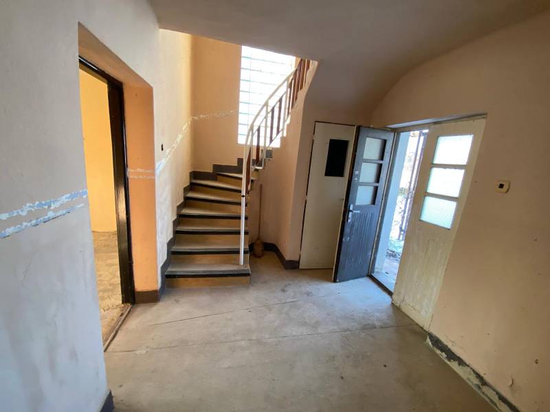 Interior of a family house with a concrete floor, stairs, and open doors.