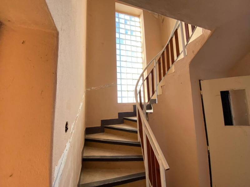 A staircase with a railing in a family house, illuminated by a large window with glass blocks.