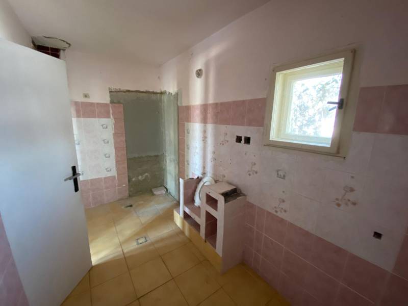 A room in a family house with pink tiles, a small window, and a yellow floor.