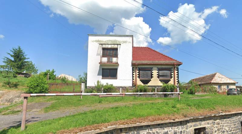 A family house in Nová Bašta with a white facade, a red roof, and a green lawn.