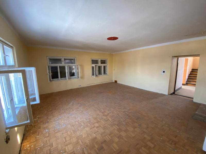 Empty room with wood-patterned flooring and windows in a family house.