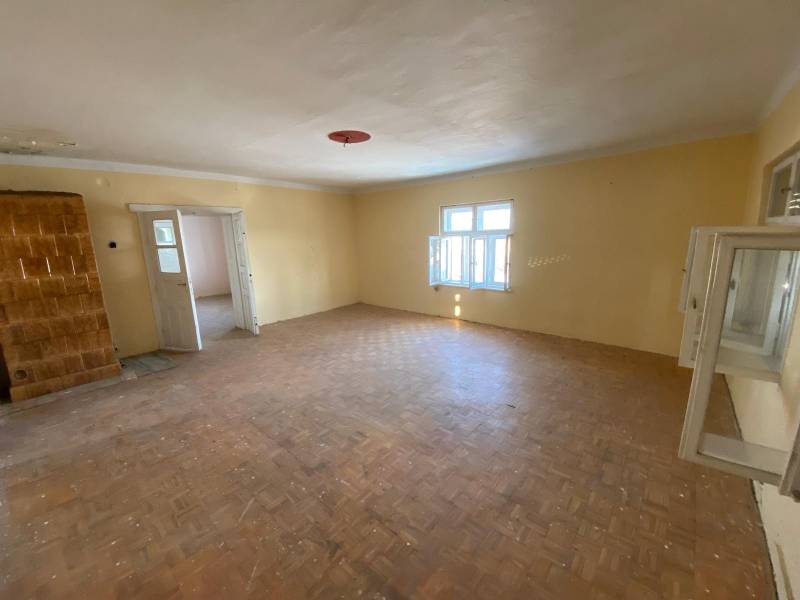 A spacious room with a wood-patterned floor and open white windows.