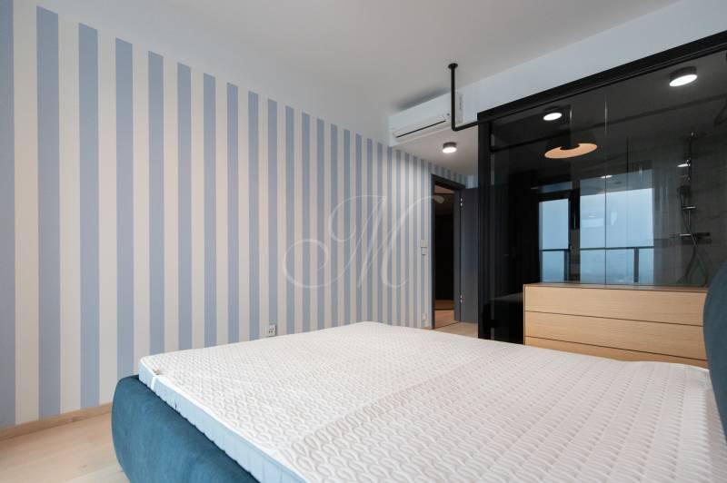 Bedroom in a 2-room apartment with a patterned wall, bed, and air conditioning.