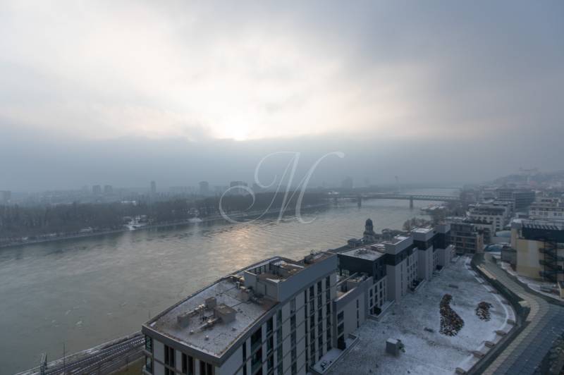 Winter panorama of Pribinova Street in Bratislava, snow-covered roofs and the Danube River.
