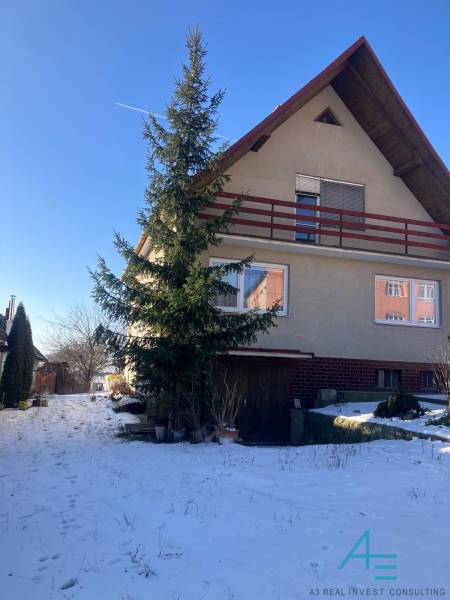 A family house in Rudník, with a gabled roof, trees, and a snowy yard.