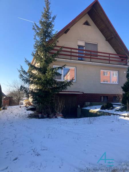 Family house in Rudník on Rudník Street with wooden cladding and a snowy garden.