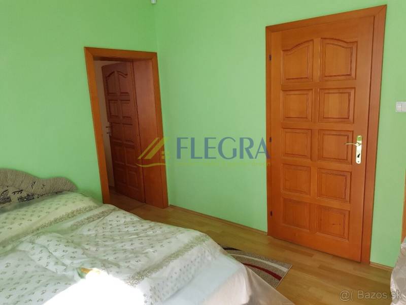 A room in a family house with a wooden decor floor, green walls, and wooden doors.