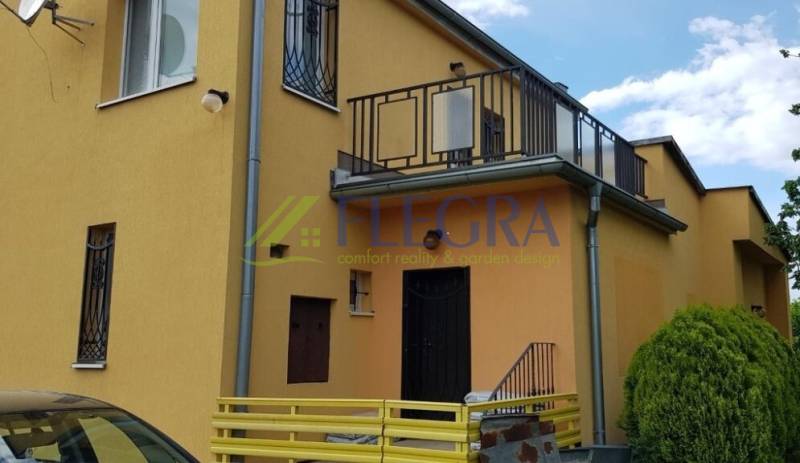 Yellow facade of a family house in Stretavka with a balcony and wrought iron window grilles.