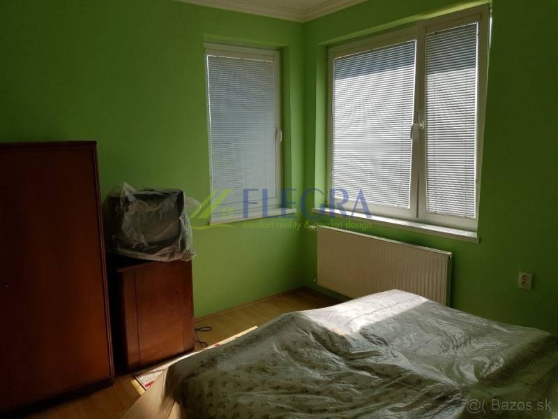 Green interior with a bed, cabinet, television, and plastic covering in a family house.