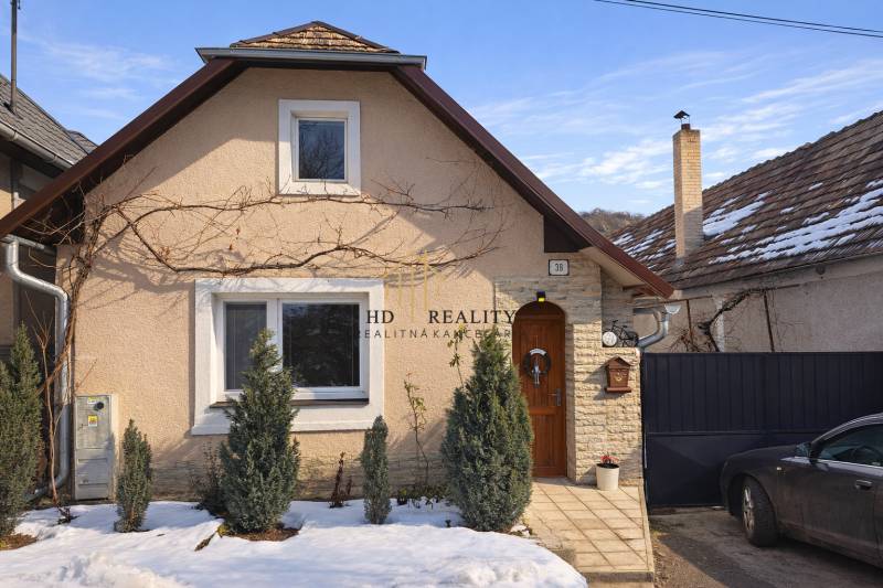 A family house in Sudince with coniferous trees in front of the entrance, a snowy scene.