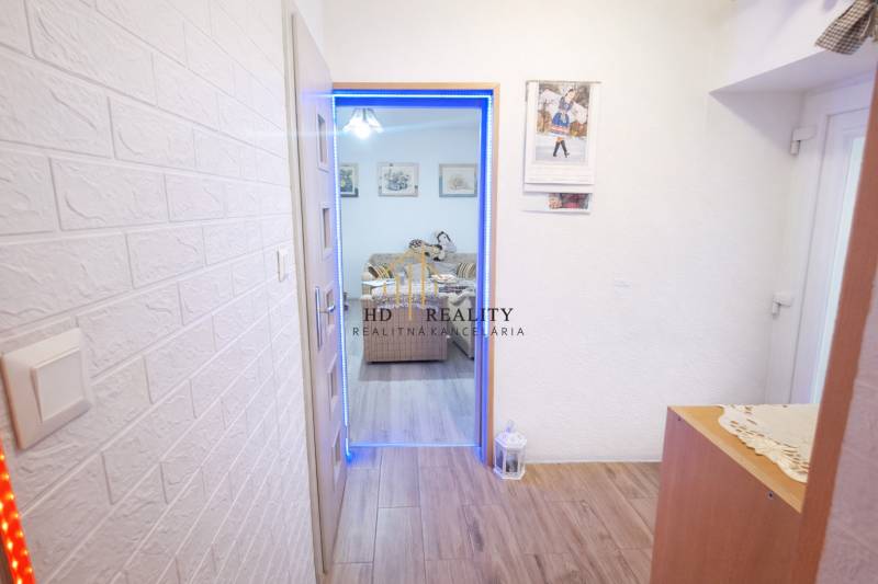 A hallway with a wood-patterned floor in a family house, leading to the living room.