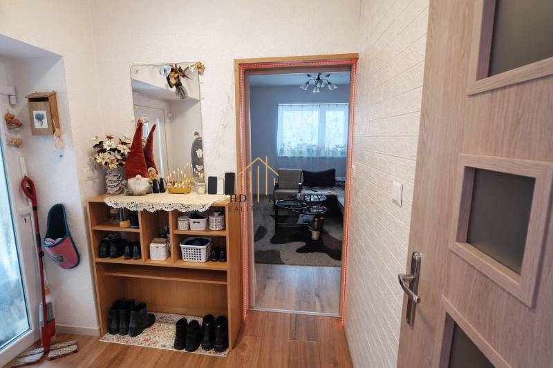 A hallway in a family house with shelves, a mirror, and a wooden-patterned floor.