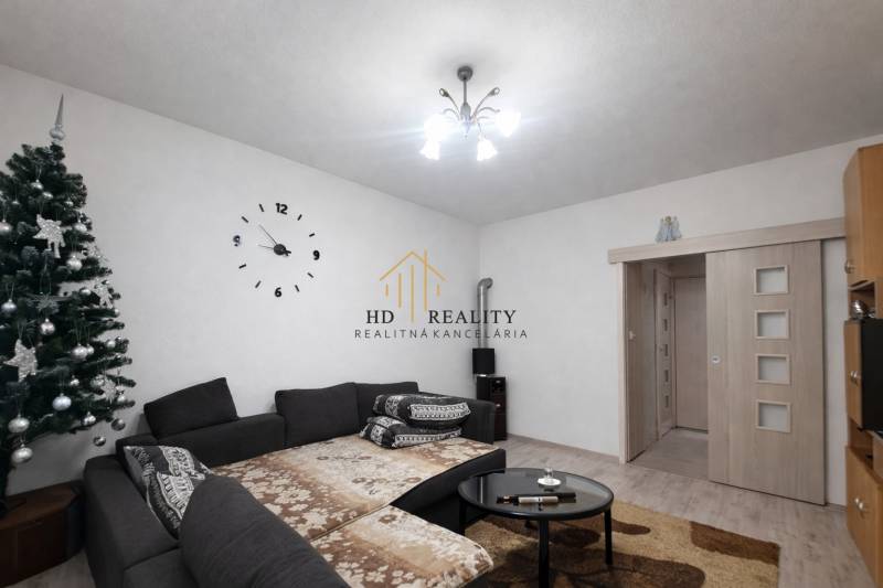 Living room in a family house with a decorated tree and a comfortable dark sofa.