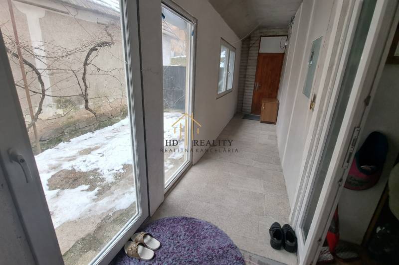 A corridor with large windows and doors, a floor with ceramic tiles in a family house.