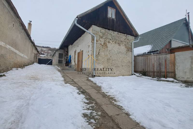 A family house in Sudince with a stone facade and a snowy yard.