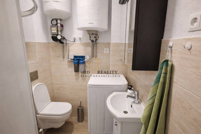 Bathroom in a family house with a toilet, washing machine, and sink.