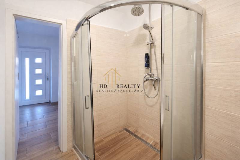 Shower enclosure and floor with wood decor in the entrance area of the family house.