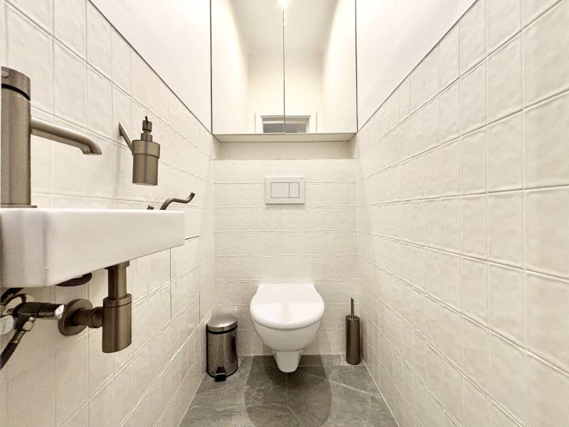 A toilet with ceramic tiles and chrome accessories in a 3-room apartment.