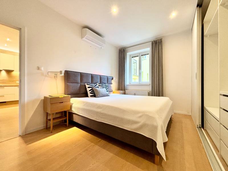 Bedroom in a 3-room apartment with a bed, nightstand, and wooden decor flooring.