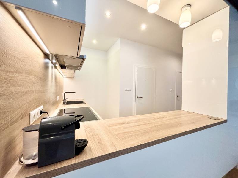 A kitchen in a 3-room apartment with a wooden decor floor and built-in lighting.