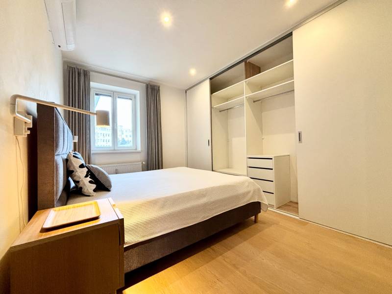A bedroom in a 3-room apartment with a large built-in wardrobe and a floor with a wooden decor.