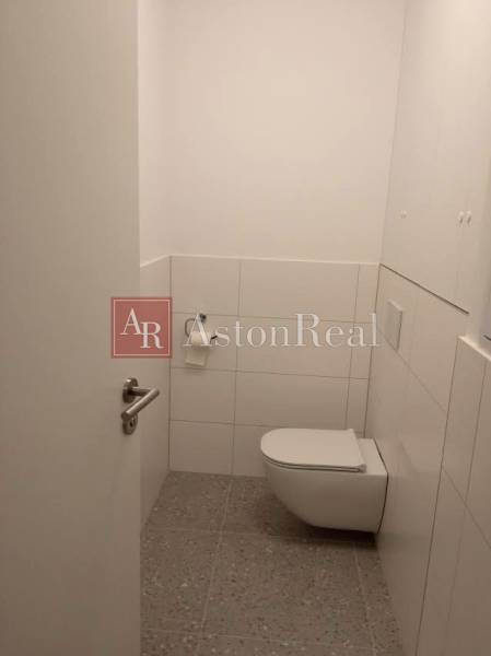 Bathroom with toilet in a 2-room apartment, white walls, tiles.