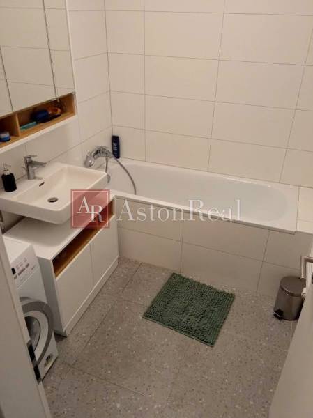 Bathroom in a 2-room apartment with a bathtub, sink, and washing machine.
