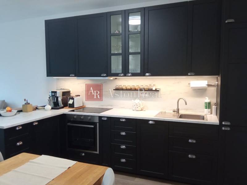 The kitchen in a 2-room apartment with dark cabinets and a wooden table decor.