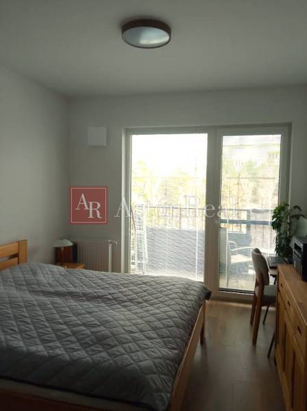 Bedroom in a 2-room apartment with a bed and a balcony, floor with wooden decor.