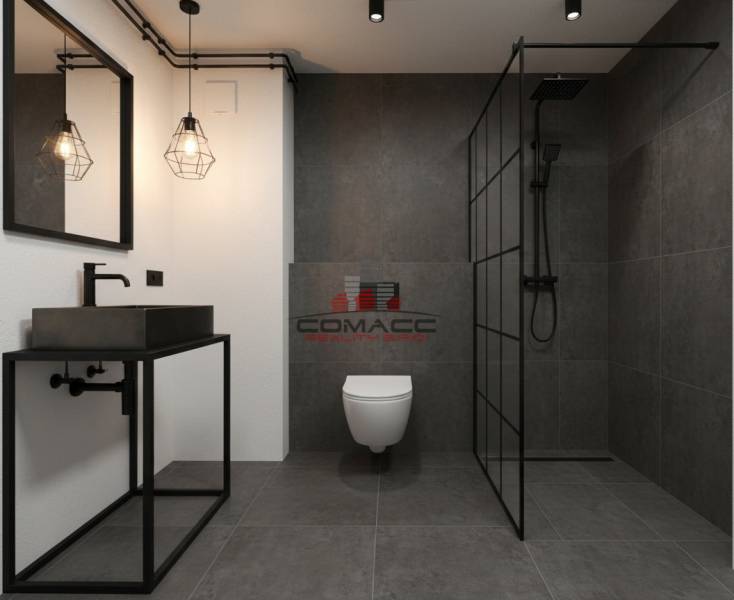 A bathroom in a family house with dark tiles and a sink on a black frame.