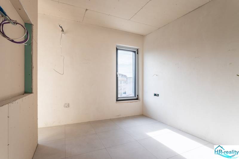 An empty room in a 3-room apartment with light-colored walls and a window with a view.