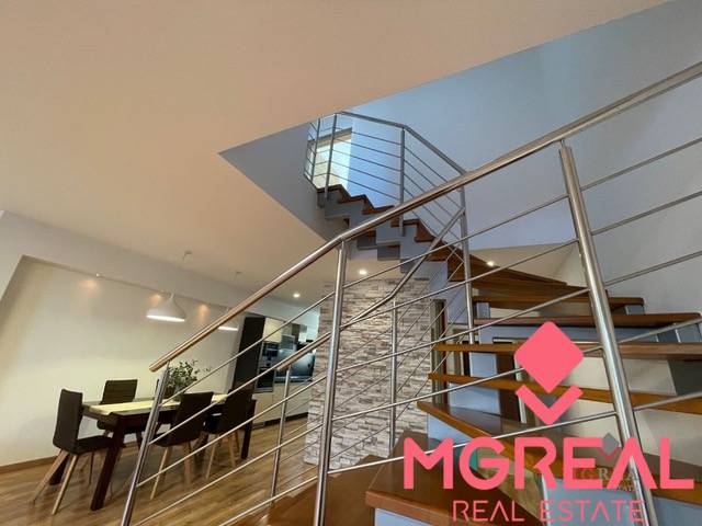 A staircase with a metal railing, a dining table, and a floor with a wooden decor in a 3-room apartment.