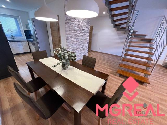 Dining room in a 3-room apartment with a wood-patterned floor and a staircase.