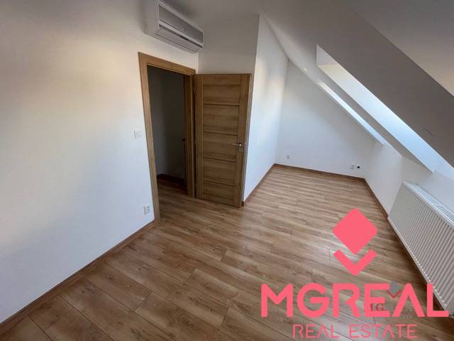 Attic with air conditioning and wooden decor flooring in a 3-room apartment.