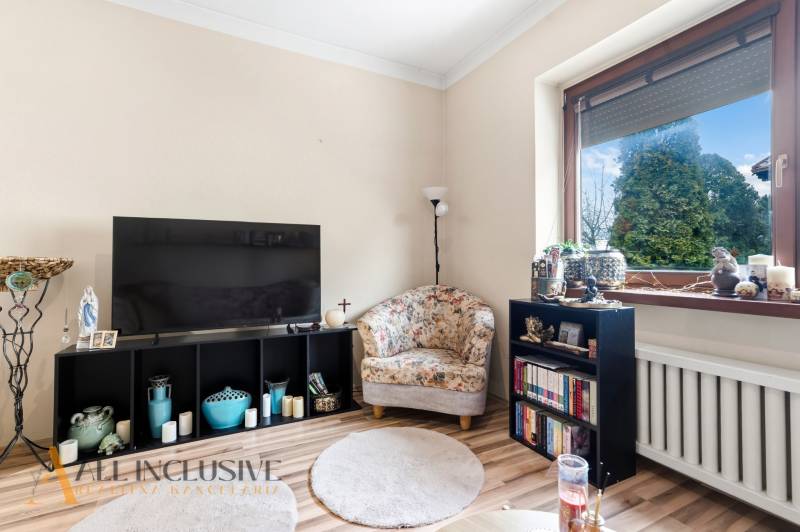Living room with a television and an armchair, wooden decor flooring, family house.