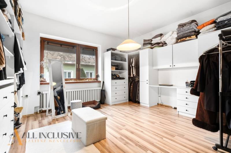 A wardrobe in a family house with white cabinets and a wooden decor floor.