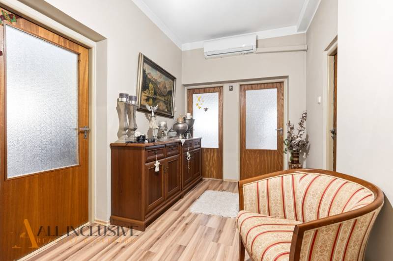 Hallway of a family house with a cabinet, chair, and wooden decor flooring.