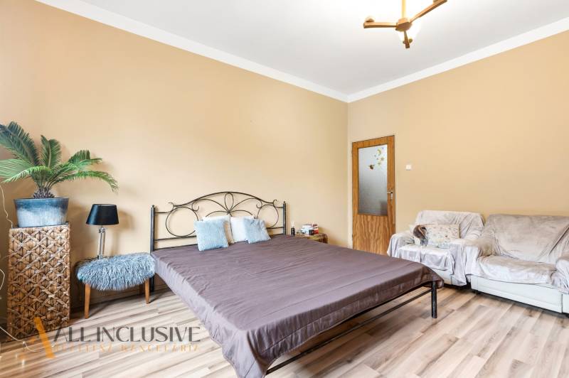 Bedroom in a family house with a bed, sofa, and wooden decor flooring.