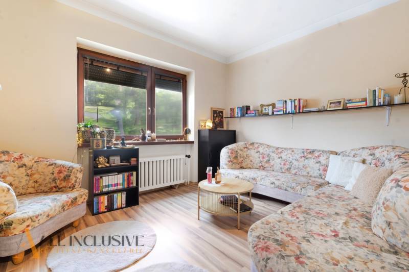 Living room in a family house with floral sofas and a wooden-patterned floor.