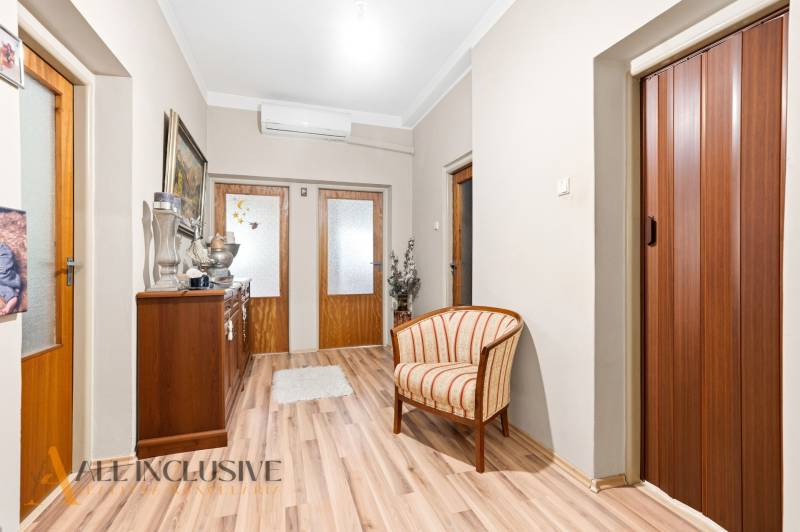 Interior of a family house with an armchair, cabinet, wooden decor flooring, and doors.