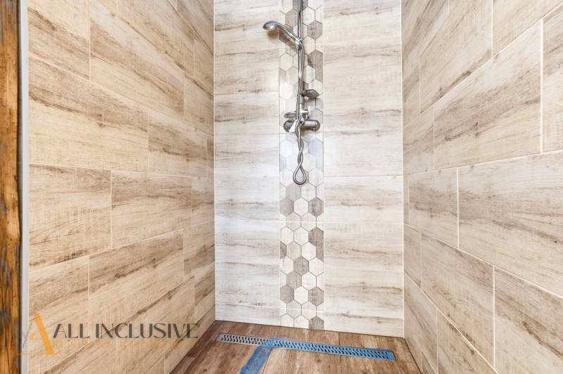 A shower enclosure in a family house with wood decor tiles and hexagonal details.