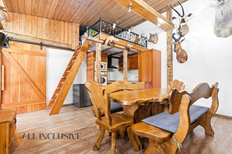 The interior of a family house with wooden furniture, a ladder, and hunting trophies on the walls.