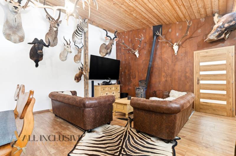 The interior of a family house with trophies, leather sofas, and a wooden decor floor.