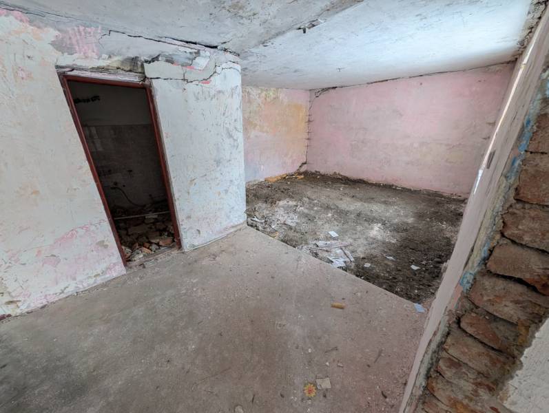 An abandoned room in a family house with bare walls and a broken floor.