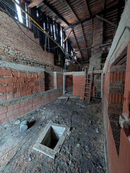 Unfinished interior in a family house with an exposed ceiling and brick walls.