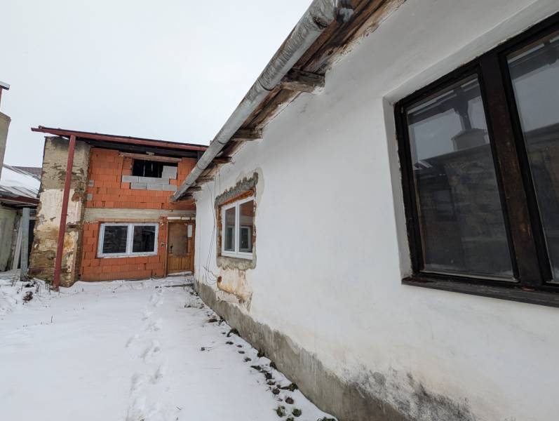 Snow-covered yard of a family house on Remeselnícka Street in Ľubica, brick and plastered walls.