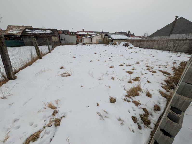 A snow-covered plot in Ľubica on Remeselnícka Street, surrounded by fences and family house buildings.